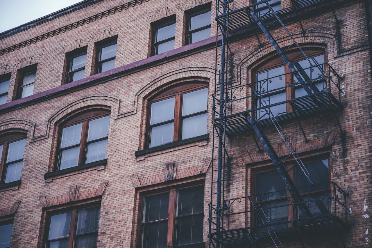 Classic brick building exterior featuring arched windows and an iron fire escape.